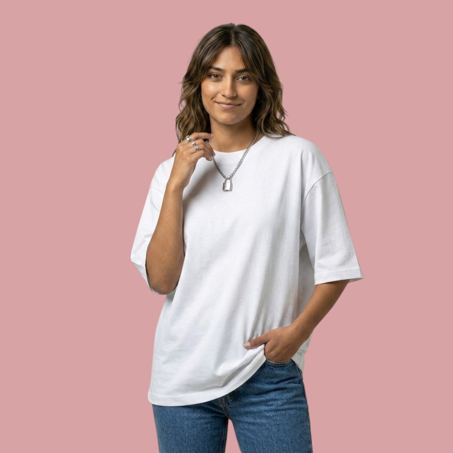 Front view of a smiling female model wearing an oversized, plain white streetwear t-shirt from the Dan Da Dan anime collection, styled with blue jeans and a silver padlock necklace.