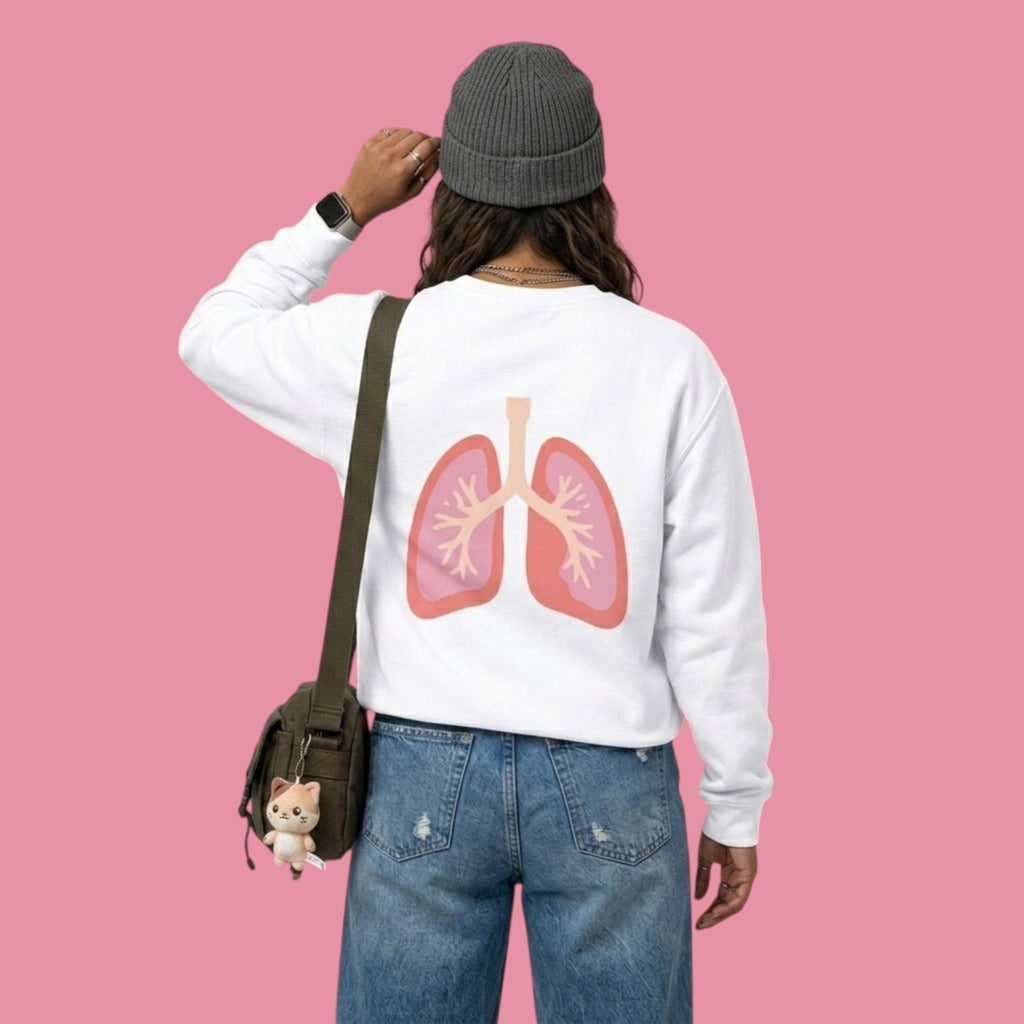 Back view of a model wearing a white Dan da Dan anime collection sweatshirt featuring a large pink and red anatomical lung illustration. The model is wearing a grey beanie, blue jeans, and a green crossbody bag with a small cat plushie keychain.