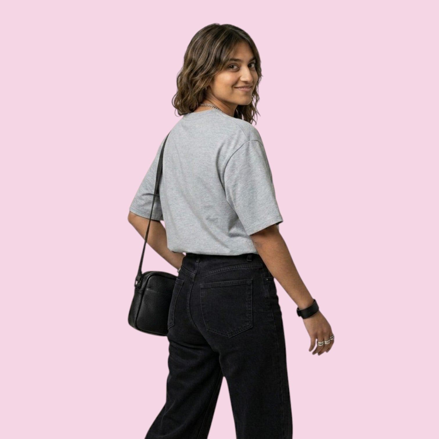 Back and side view of a woman wearing the Momo Ayase Dan Da Dan inspired grey oversized tee, styled with black jeans and a crossbody bag