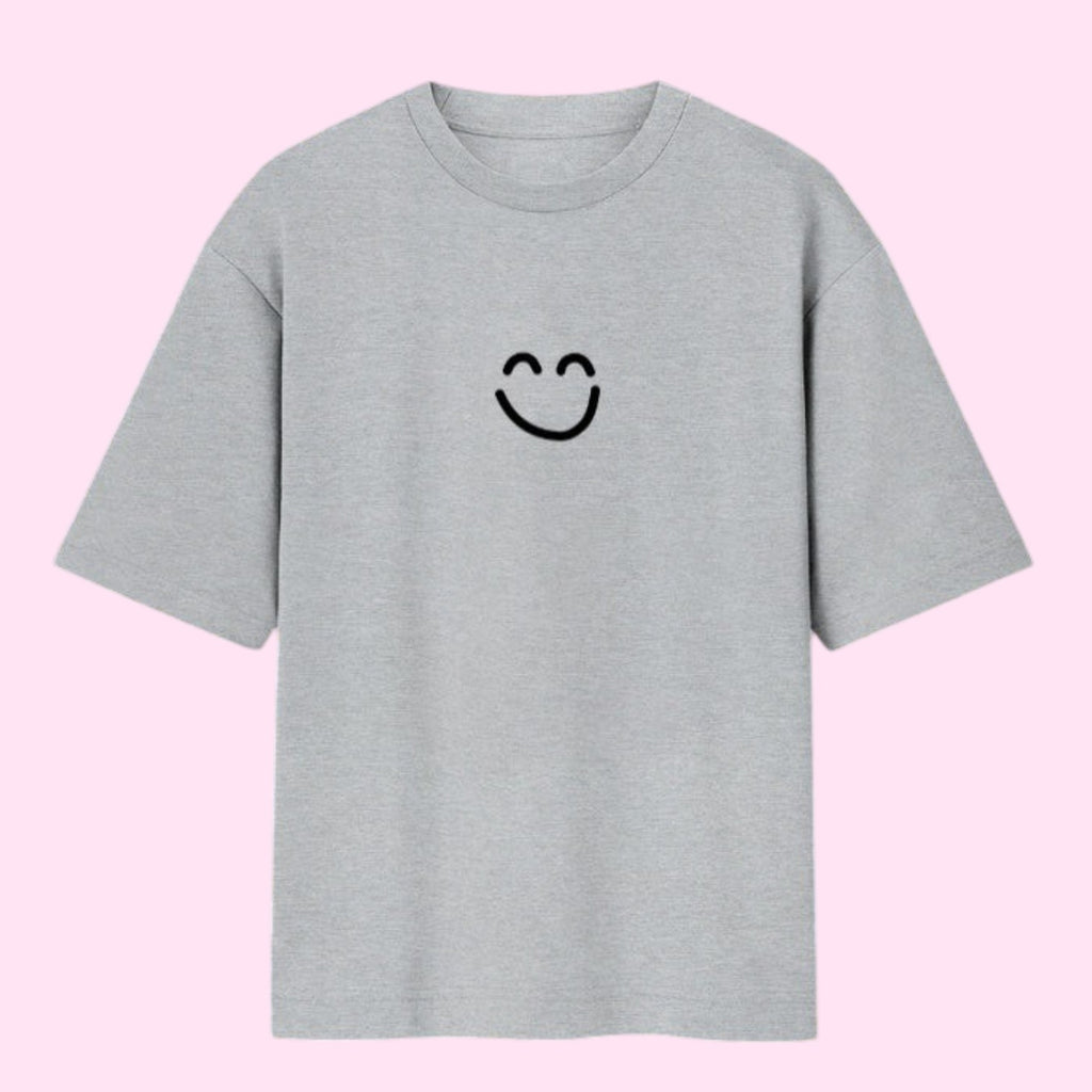 Front view of a flat light grey oversized streetwear t-shirt featuring Momo Ayase's black smiley face graphic from Dan Da Dan Season 1.